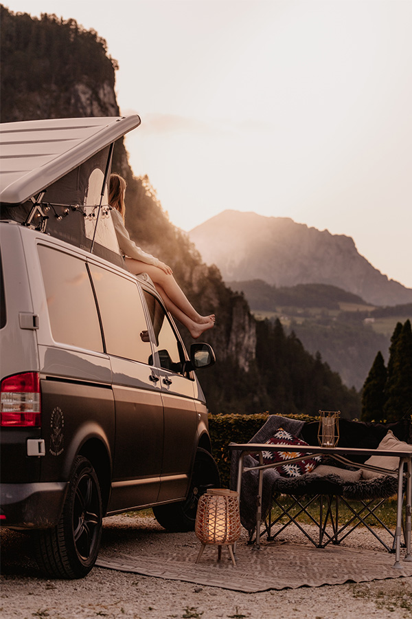 Campingbus vor Felswand und Bergen im Abendlicht