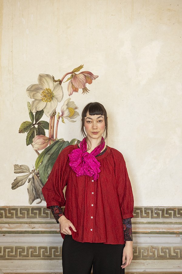 Modell in roter Bluse mit pinkfarbenem Tuch
