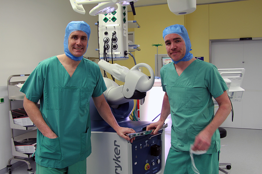Zwei Ärzte in OP-Kleidung neben einem Robotersystem