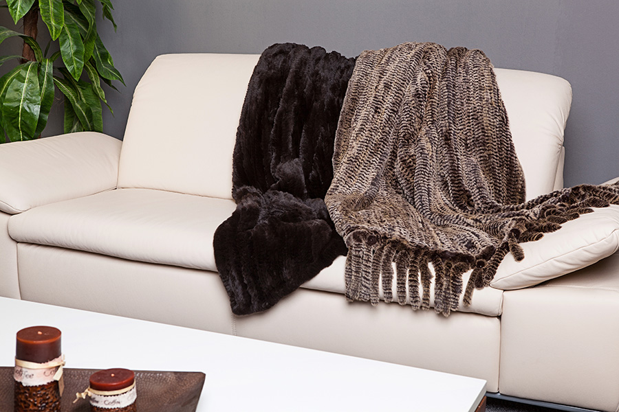 Zwei dunkle Felldecken auf einem Sofa