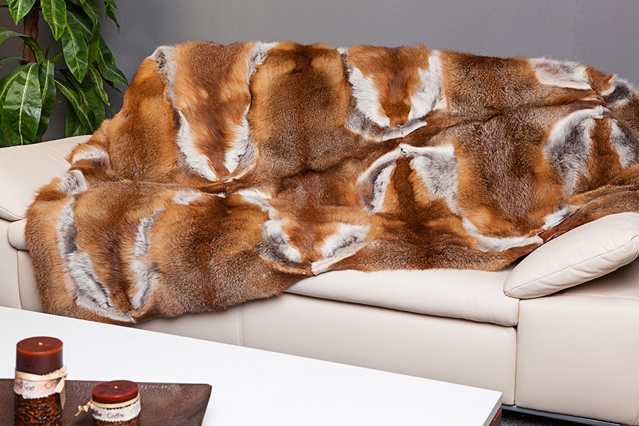 Felldecke in warmen Brauntönen auf einem Sofa
