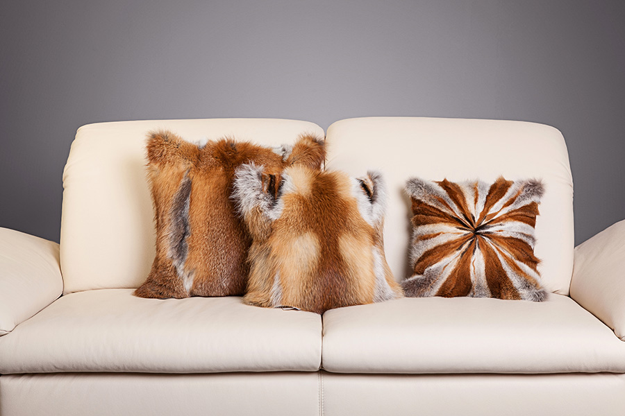 Drei Fellkissen auf einem Sofa