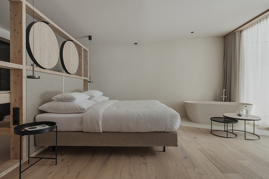Helles Zimmer mit Holz, Doppelbett und freistehender Badewanne
