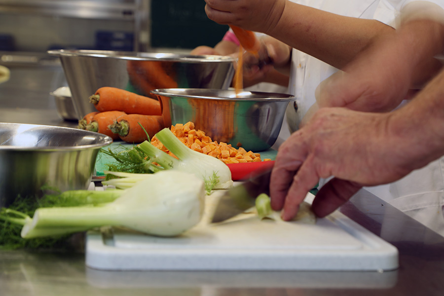 Hände schneiden frisches Gemüse in der Küche