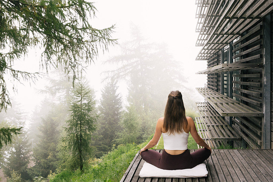 Frau beim Yoga auf der Holzterrasse im Nebel