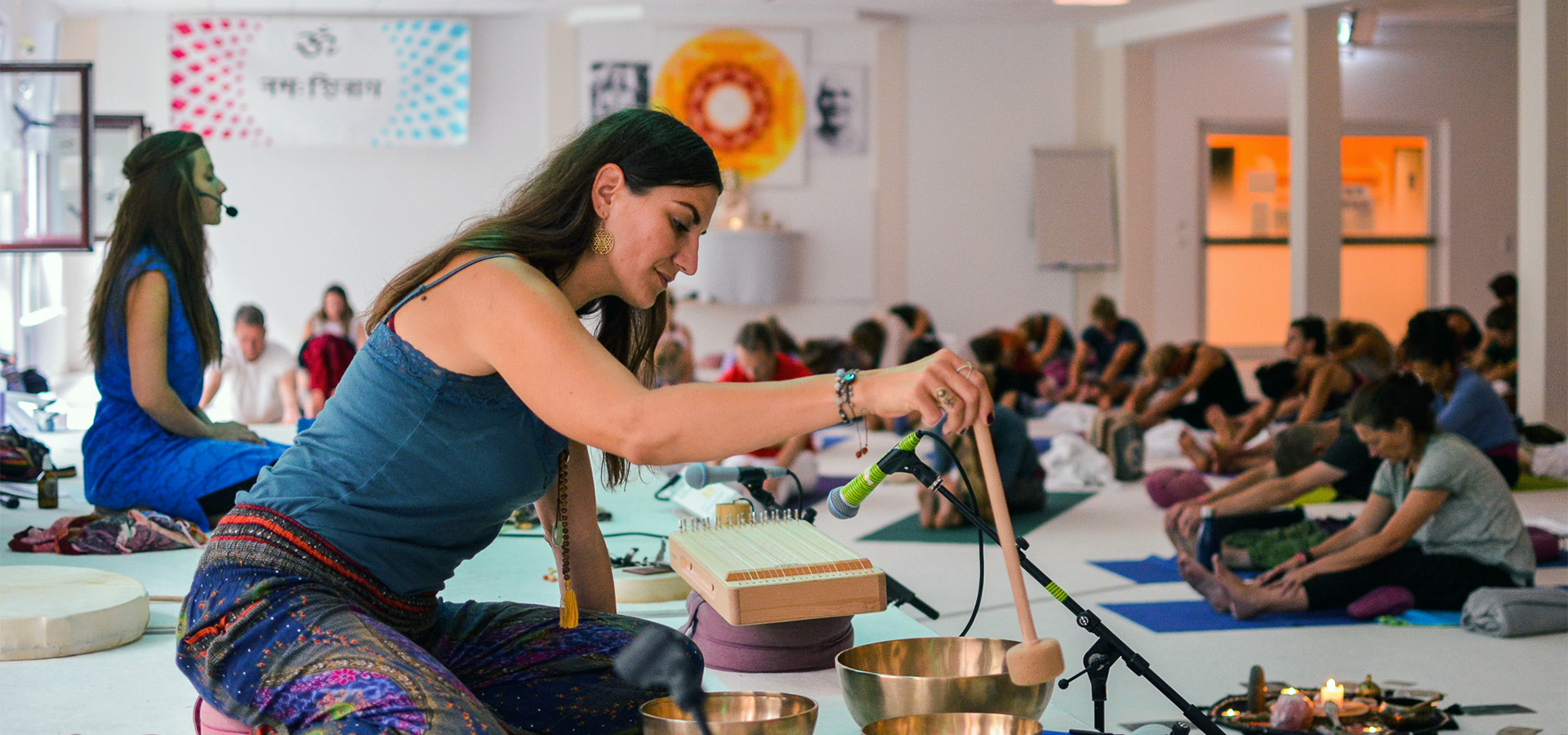 Seminarleiterin mit Klangschalen vor einer Yogagruppe